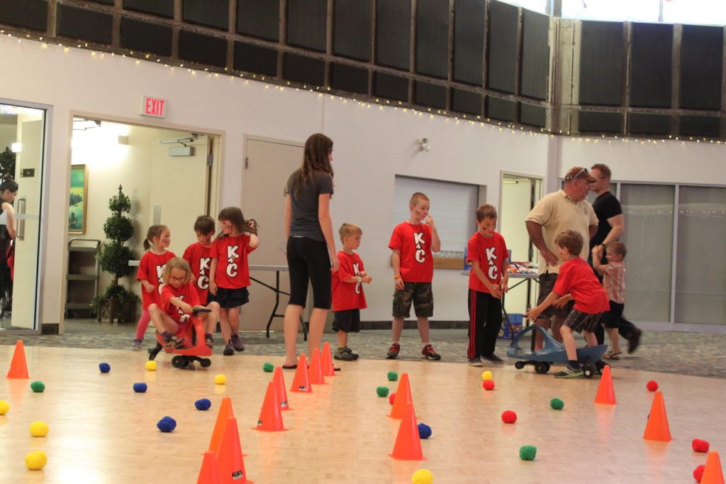 Children in red shirts playing games with cones in the parish hall