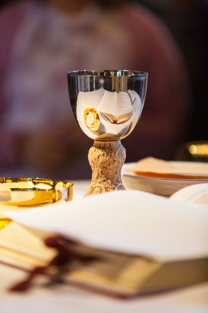 Chalice, hosts and open Bible Communion chalice with hosts beside an open Bible